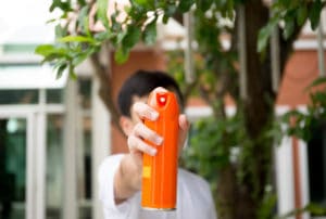 Hand holding insect spray can outdoor